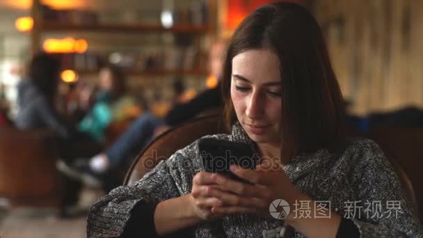 年轻女子坐在咖啡馆中使用手机视频