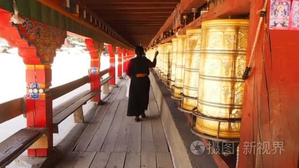 藏族妇女通过祷告鼓的四川省，中国的佛教 templei 行行走时祈祷