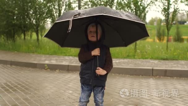小男孩玩了一把伞在一个下雨天视频