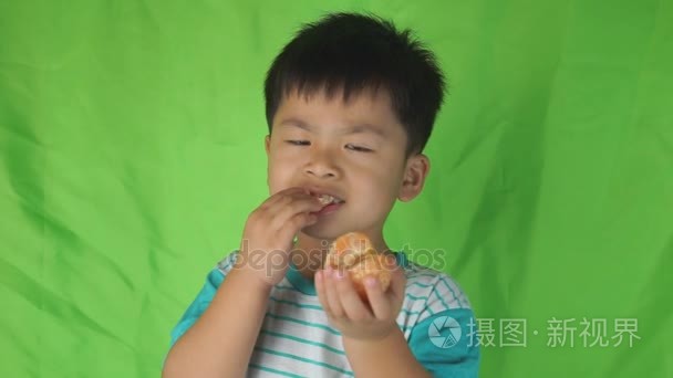 在绿色背景上吃橙子的可爱男孩视频