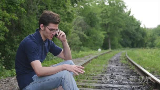 年轻男子通过电话谈铁路轨道视频