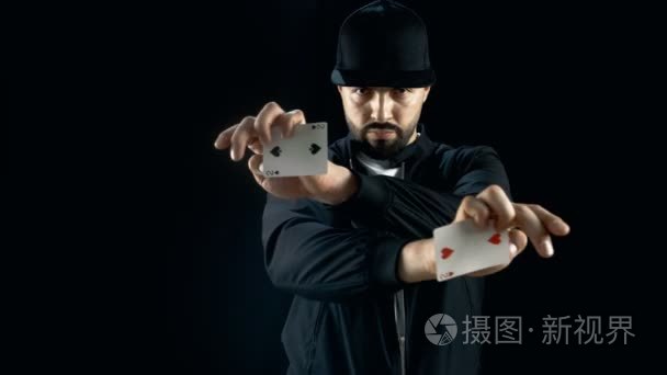 专业街头魔术师帽执行令人印象深刻的花招纸牌戏法。背景是黑色