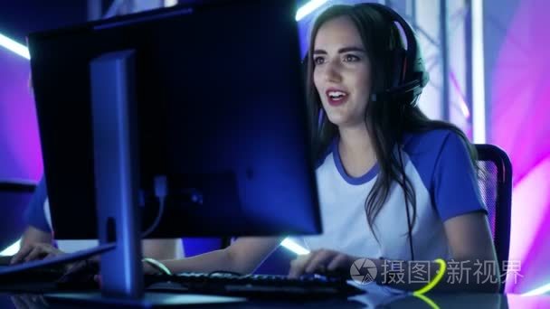 美丽的专业玩家女孩和她的团队参加电子竞技网络游戏比赛。她有耳机和多彩带