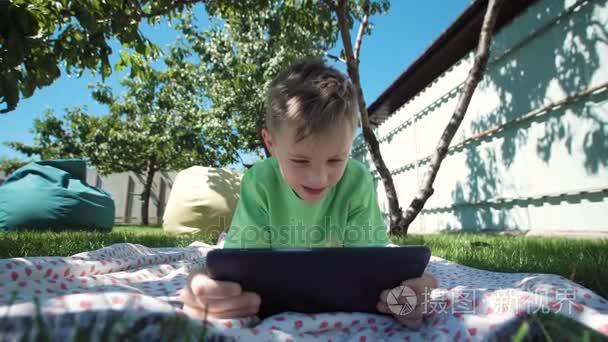 男孩在花园里的平板电脑与通信视频