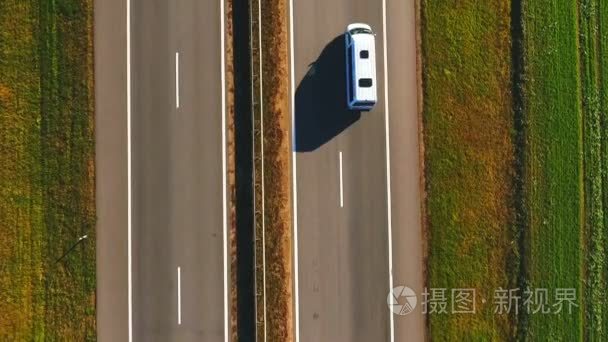 顶视图开车慢慢地沿着公路。郊区的道路上行驶的汽车