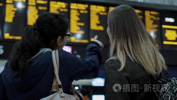两个女孩检查在火车站离境表视频