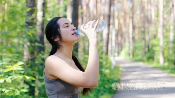 女孩浇灌自己从一个瓶子里的水视频