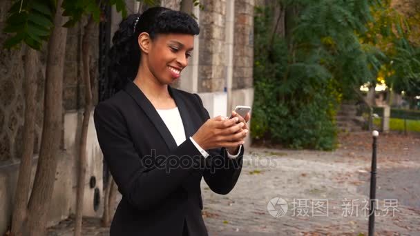 心爱的黑白混血儿女孩在公园里用智能手机写消息