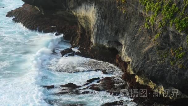 海浪拍打着热带海滩上的岩石  形成了飞溅的形状。在岩石海滩上的强浪。印尼巴厘岛著名的乌鲁瓦图寺