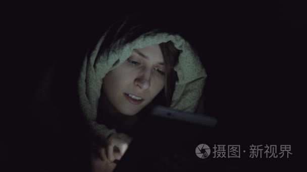 女性在夜间使用数字平板电脑视频