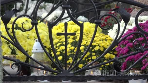 在公墓的金属十字架的蜡烛淡黄色菊花.4k短视频