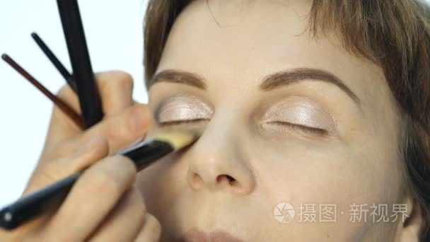 在眼睑上涂抹眼线的专业化妆师特写。时尚行业化妆品