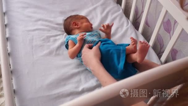 一个年轻的母亲给新生儿穿衣服视频