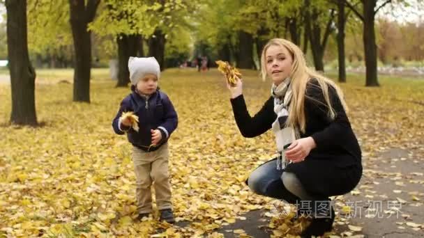 母亲和儿子在公园里扔黄叶子视频
