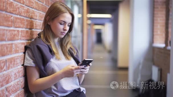 漂亮的年轻女人发短信在砖走廊视频