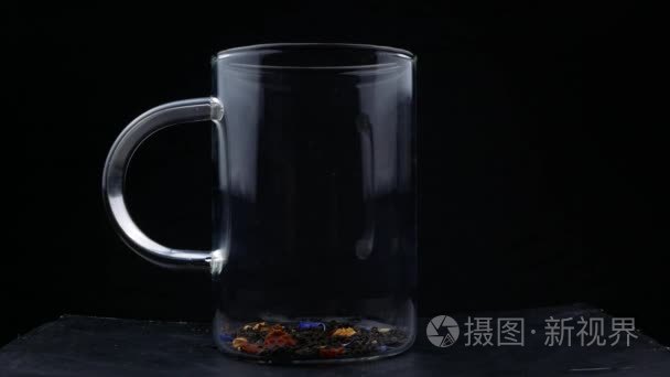 玻璃杯中的茶叶中注入开水的宏观镜头。红茶的酿造。玻璃透明茶壶酿造凉茶过程的宏拍视频