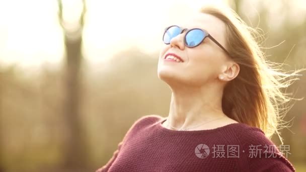 一个漂亮的三十岁的戴眼镜的女人把她的脸放在了春天的阳光下。他安排他的手, 走向风。与自然的统一。享受春热