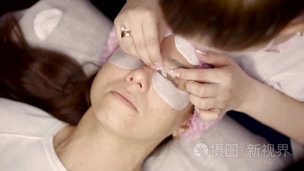关闭拍摄的一个化妆艺术家做睫毛为她的客户室内