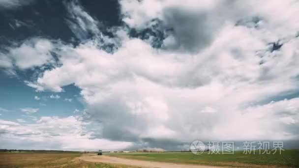 农村公路 Timelapse 的时间推移时间推移通过田间春季草地景观在风景剧烈的天空下, 在雨前蓬松的云层。农业天气预报概念视频