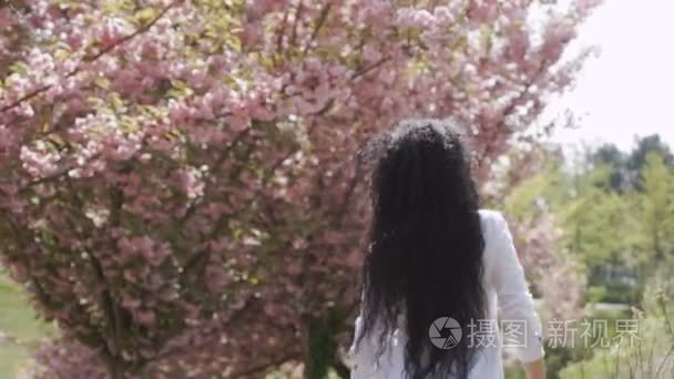 穿着白色连衣裙的女人走在盛开的樱花树旁, 慢动作