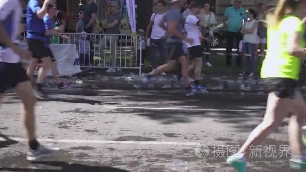 马拉松赛跑者脚下的水塑料杯视频