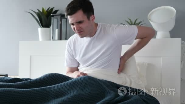 背部疼痛的男子坐在床上视频