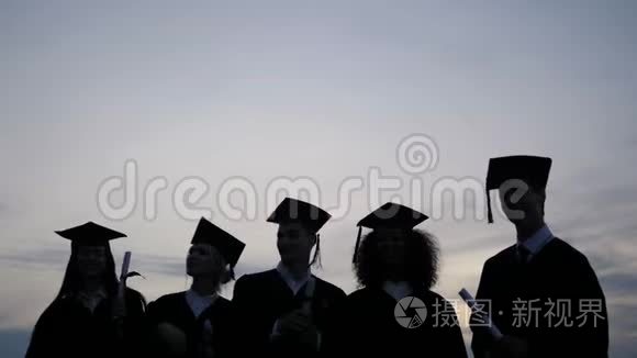 庆祝教育毕业学生成功学习理念。 学生在空中抛帽子的剪影。