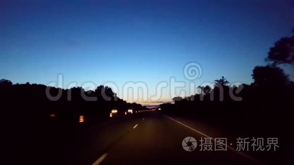 在地平线上用灯光驾驶早晨的高速公路。 司机观点POV州际驾驶清晨。 高速公路