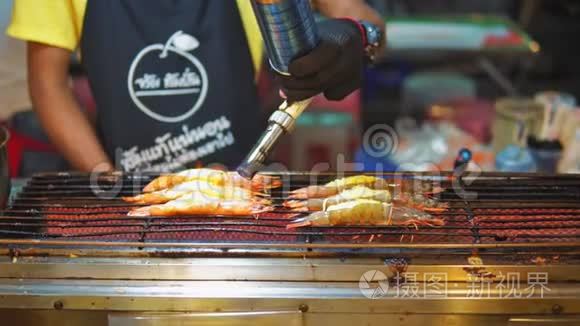 亚洲街头美食，亚洲传统菜肴。 海鲜虾在烤架上，厨师烤他们的燃烧器。 夜食市场