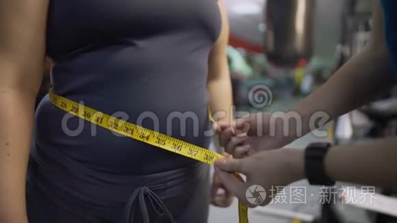 健身教练测量女性腹部，健康饮食和锻炼结果控制