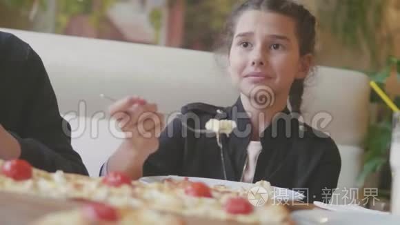 少女在咖啡厅慢动作视频里吃披萨。 孩子们吃比萨饼，吃美味的比萨饼。 人们的生活方式