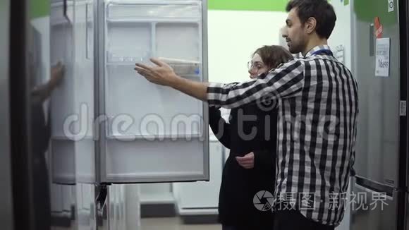 年轻夫妇在购买消费电子产品商店前先检查开门冰箱设计和质量