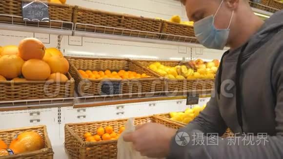 带医疗面罩的人在商店里挑选曼达林。 男人在超市里选择水果。 购买农产品