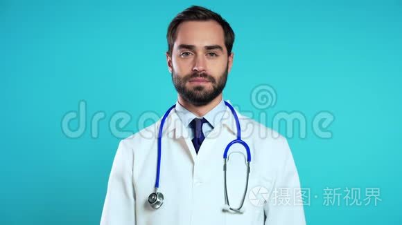 穿着职业医疗白大褂的英俊男子的肖像被隔离在蓝色上