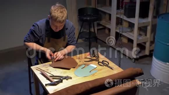 男人在桌子上剪一块布做鞋子视频