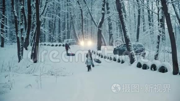 孩子们在下雪的冬天森林里玩充气戒指。 停在附近的汽车