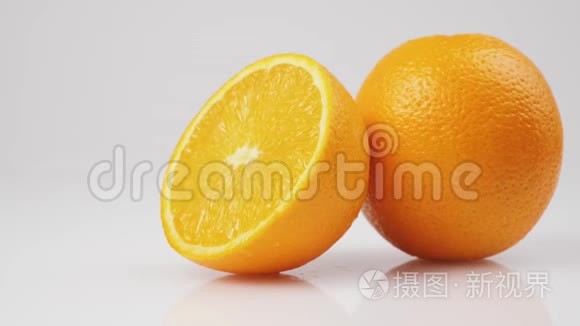 两个新鲜橙子的中间镜头在白色背景的白色桌子上旋转，孤立地旋转