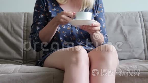 坐在沙发上，坐着教练，喝着热咖啡或茶，穿着休闲装的女人面目全非，她在做了之后很放松