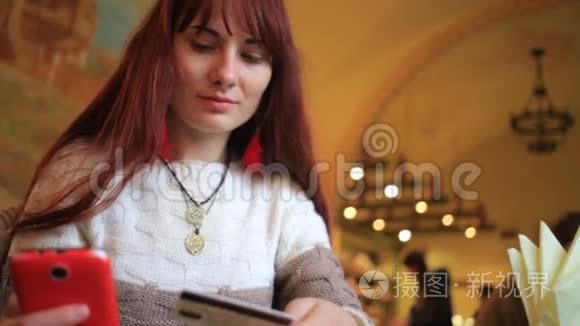 美丽的女子网上银行使用智能手机在线购物，信用卡在咖啡馆的生活方式