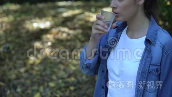 女人喝水扔掉杯子，全球塑料过度消费