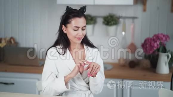 穿浴袍的女人的肖像在她的脸上涂上奶油，做面部按摩