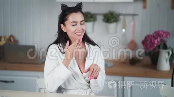 穿浴袍的女人的肖像在她的脸上涂上奶油，做面部按摩