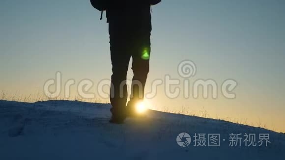 旅行者克服困难走向胜利. 旅行者在阳光的照耀下在一座雪山上站起来。 游客