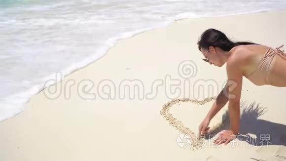 沙滩上的年轻女子在白沙上画画视频
