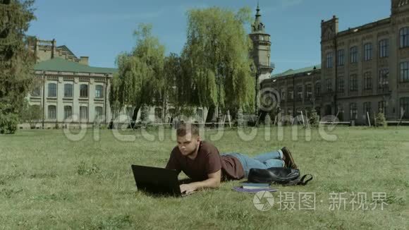 聪明的男生在校园草坪上工作视频