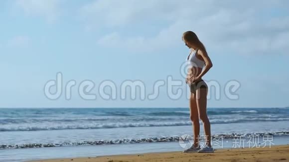 女孩穿着运动服`腿站在海洋附近，缓慢地抚摸着她的头发。