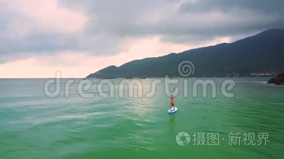 船帆上的女孩沿着海岸，泡沫般的波浪在沙滩上翻滚