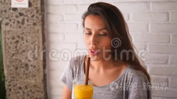 迷人的年轻混合女孩喝芒果和纯素超级食物冰沙饮料。 4K慢运动健康生活方式理念。 乌布德，