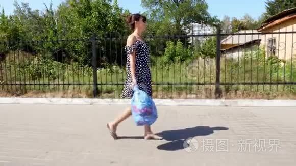 一个戴太阳镜的漂亮女孩手里拿着一包垃圾，扔垃圾。 夏日炎炎