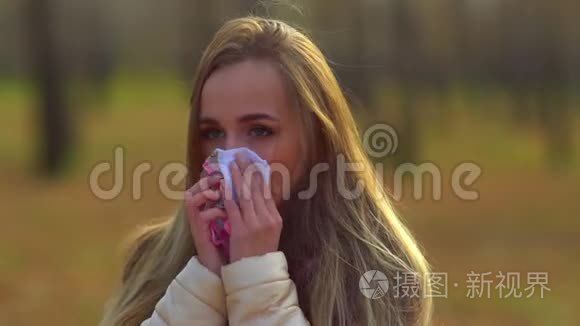 年轻迷人的女孩，在街上感冒了，用餐巾擦鼻子。